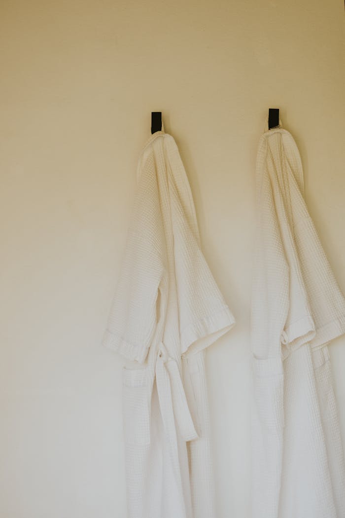 Two white bathrobes hanging elegantly on hooks, representing comfort and relaxation in a minimalist style.